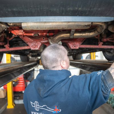 mechanic underneath a car with tailpipes